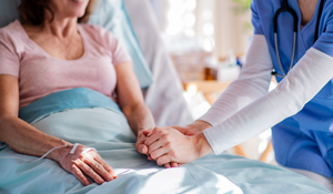 Supportive Healthcare Provider Holding Patient's Hand in Hospital Bed