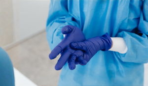 A clinician in blue scrubs and gloves